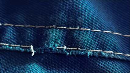 Close-up old work uniform with scuffs on a lowercase seam of blue denim