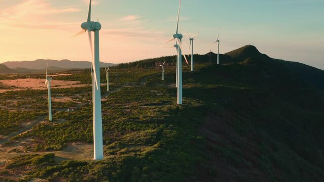 aerial shot many wind mills creating clean green energy on the top mountain at sunset sun shinning