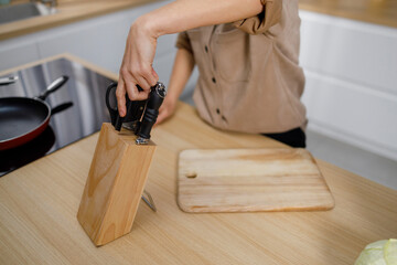 Unrecognizable woman pulls a kitchen knife out of the block before starting cooking