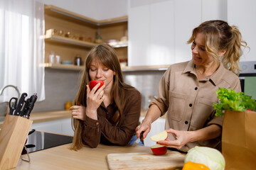 Mother cuts apples in the kitchen and treated her adult daughter to a slice
