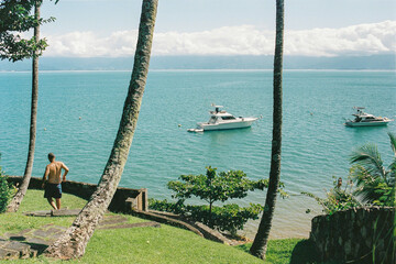 Person walking to beach in paradise island with clear water and boats in ilha bela, s&atilde;o paulo, brazil