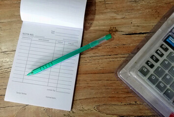 Small notebook,pen and calculator,placed on brown wooden table.Bussiness concept