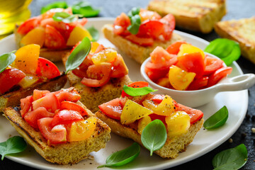 Bruschetta with tomatoes and basil on a toasted baguette on a plate. Healthy Italian snack. Close up. Selective focus