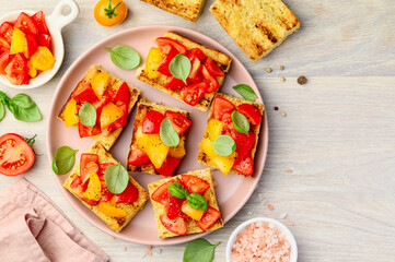 Bruschetta on a toasted baguette with red and yellow tomatoes and basil on a plate. Healthy Italian snack. Top view