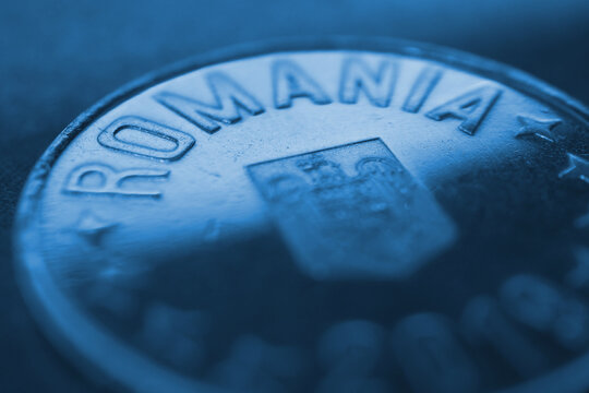 Fragment of a Romanian 50 bani coin. Inscription Romania close-up. News about economy or currency. Loan and credit. Tax and inflation. Dark money background. Blue tinted wallpaper. Macro