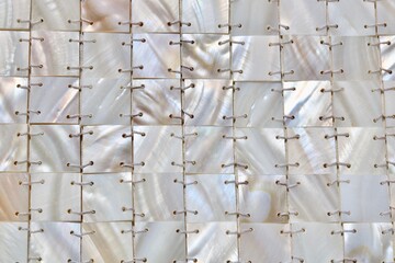Full frame background of mother of pearl stitched in square geometric design