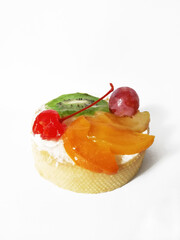 cake with cream, cherry, grapes, sliced kiwi and mango on a white background