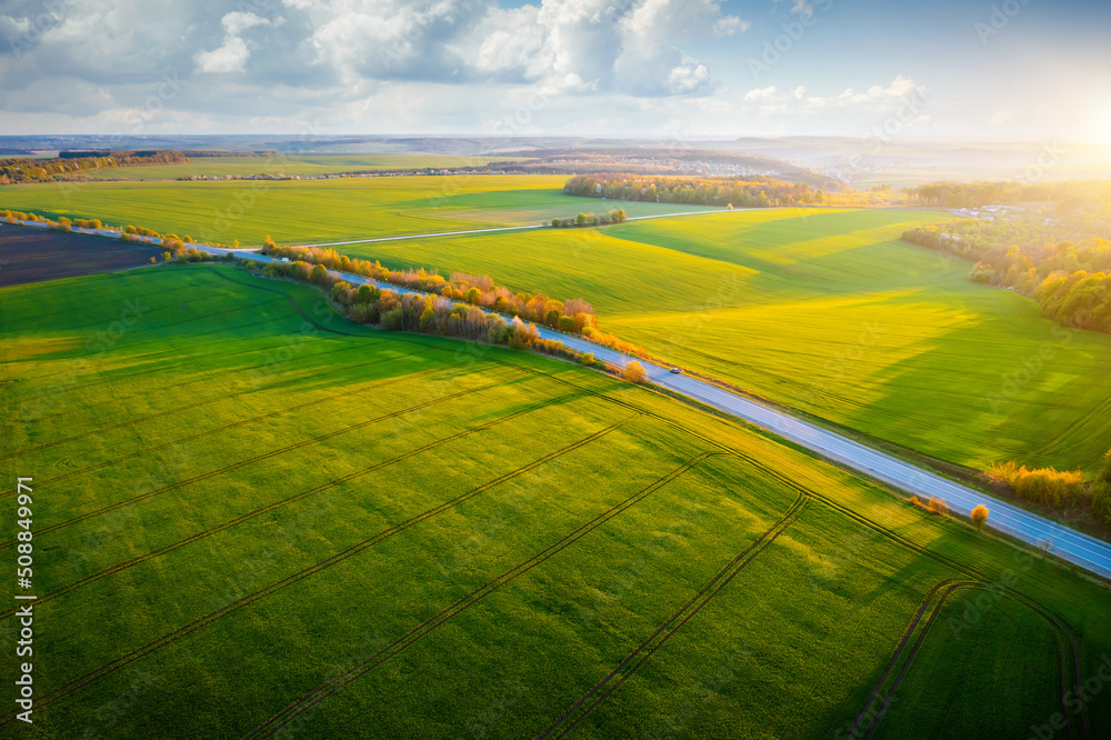 Sticker Bird's eye view of rural road passing through agricultural land and green fields.