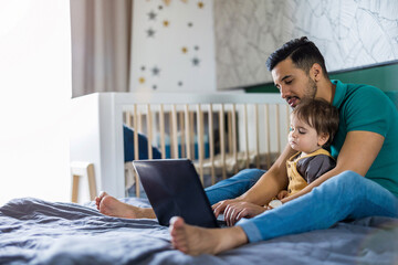 Young man and his son using a laptop at home
