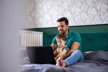 Young man and his son using a laptop at home