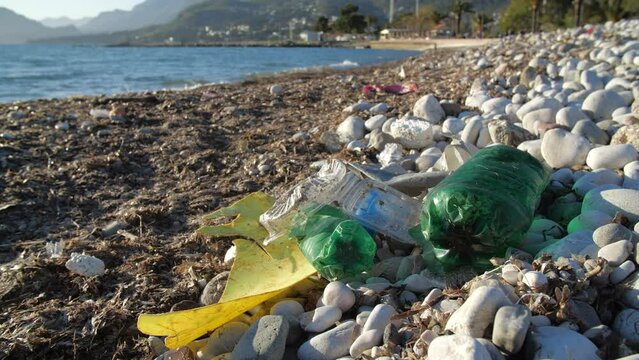 Ecological problem and environmental pollution concept. Scattered trash on the beach. Empty used dirty plastic bottles. Environmental pollution. Leaving people in the background
