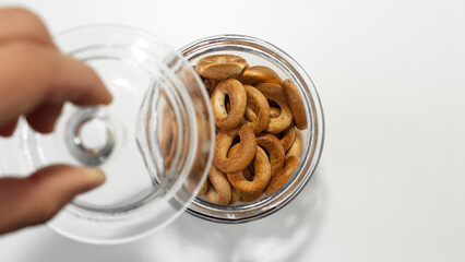 Close-up of male hand holding a lid for jar with small bagels.