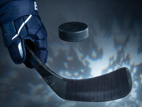 Closeup of a black ice hockey stick shooting a puck against a dreamy background.
