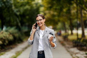 A young woman with a phone and coffee in a park.