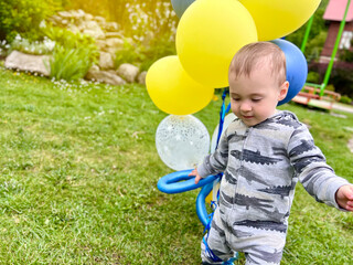 Toddler boy playing with balloons outdoors. A cute boy of one and a half years. Selective focus