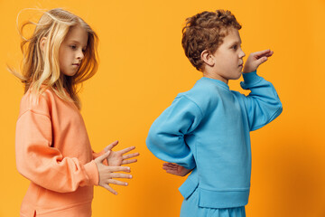 happy little children of school age stand in bright clothes on a yellow background and dance vigorously