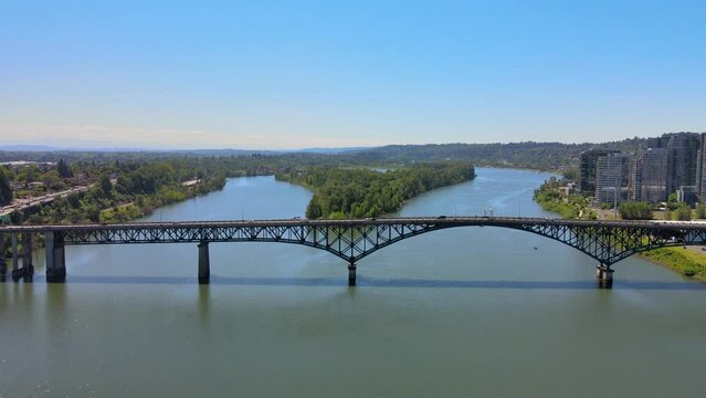 Aerial Video of a bridge crossing a river which splits into two around an island on the far side of the bridge