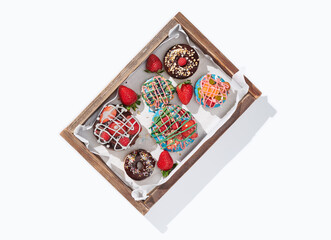 Decorated donuts with fruits in a box on white background