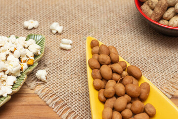 brazilian june party snacks like popcorn, peanuts and corn on straw background