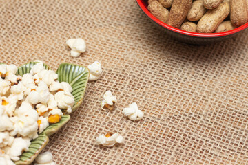 brazilian june party snacks like popcorn, peanuts and corn on straw background