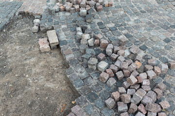 Stone pavement, construction worker laying cobblestone rocks on sand.