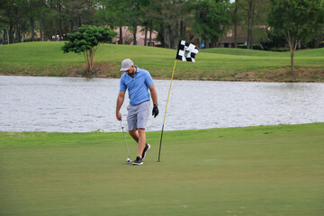 a golfer scooping up his ball