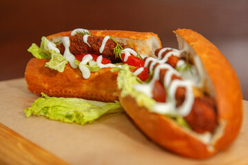 Sandwich with cutlet lies on a pacifier covered with kraft paper, and the side of the sauce to it