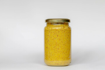 Selective focus of golden yellow mustard in glass bottle or pot on white background, Mustard is a condiment made from the seeds of a mustard plant.