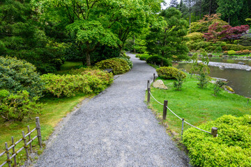 Gravel path leading the way in a peaceful Japanese garden on a wet spring day
