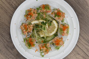 Overhead view of Asian cuisine sushi roll with lobster and shrimp tempura topped with green onion and masago for a very hearty meal