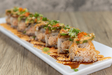 Asian cuisine sushi roll with fish and crab mixed with cucumber and topped with eel, green onion, and jalapeno for a very hearty meal