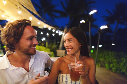Dating couple drinking on date night out at restaurant Outdoor bar people drinking cocktails friends laughing dating couple happy nightlife lifestyle, Hawaii, USA.