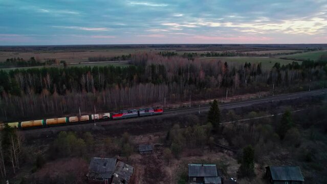 A train with tank passes by the village.