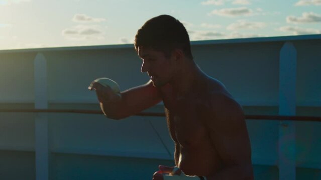 Young strong man with naked torso exercising box outdoors onboard cruise ship