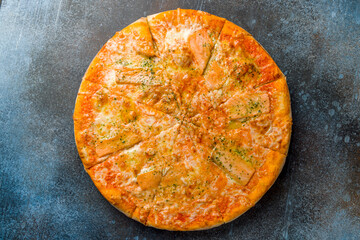 Pizza with salmon and cheese with tomato sauce top view on dark blue stone table