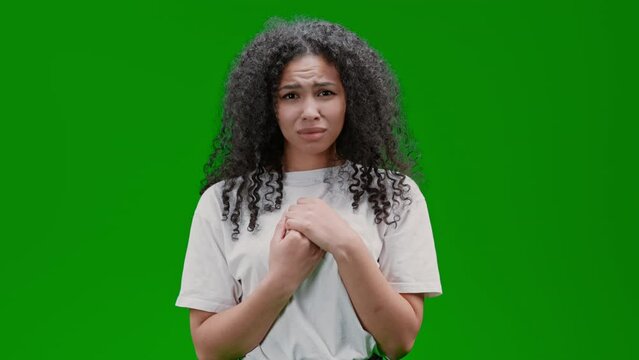 unhappy woman with curly long hair dressed white shirt express regret for something Isolated on Green Screen