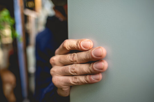 Closeup of a beautiful and stylized hand of worker with blue hoodie holding a metal door in the day
