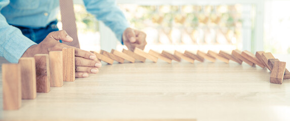 Close-up hand prevent wooden block not falling domino concepts of financial risk management and...