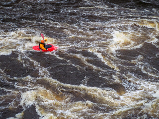 Man whitewater kayaks down a big river in a red playboat