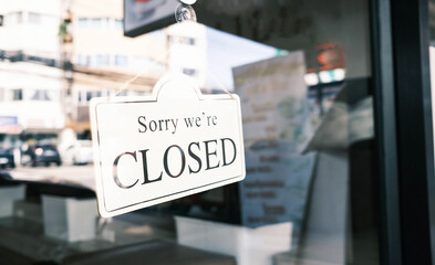 Sign text hangs on the entrance door of the shop, restaurant, cafe. That reads "Sorry, we're closed". Closed due to financial difficulties and economic crisis.