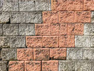 The wall surface is made of bricks in two colors. Taken outside of a strong land where there are shadows.