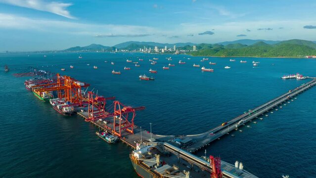Timelapse of Aerial view Truck running on the long bridge to big crane for load cargo container to cargo vessel ship at international yard port import export freight shipping by ship