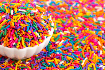 Fototapeta na wymiar A Bowl of Rainbow Sprinkles on a Table of Sprinkles