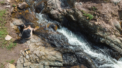 Aerial view of Woman relaxing with beautiful natural water stream the wild forest mountain concept traveling and relaxing on holiday time.