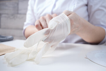 Professional manicurist puts on white medical gloves - obrazy, fototapety, plakaty