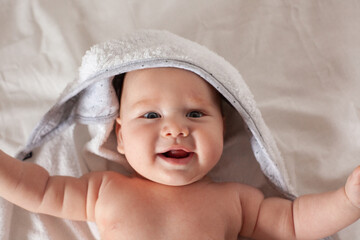 a small baby lies on the bed in a towel.Baby care.