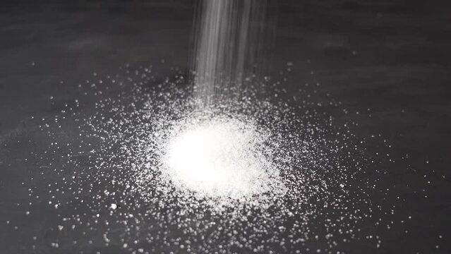 granulated sugar. pouring sugar on a black background.