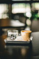 Selective latte cup of coffee on a table with the drinking water