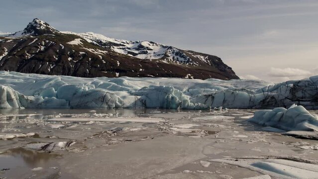 Flying drone shot of a Sv&iacute;nafellsj&ouml;kull Icland glacier melting in a brown river, Iceland in winter