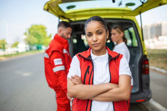 Young female african american paramedic standing rear of the ambulance. paramedics by the ambulance. Two paramedics taking out strecher from ambulance